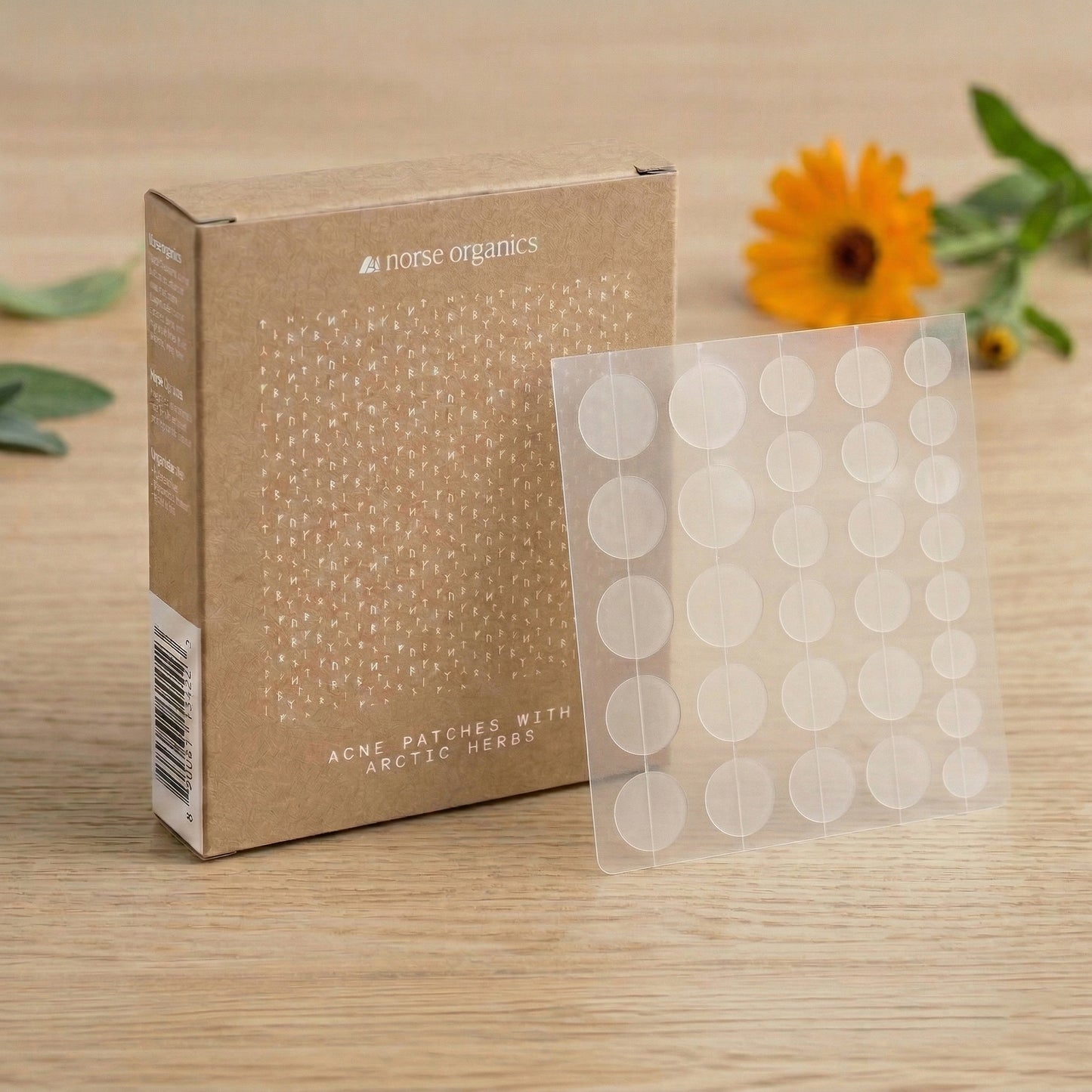 Acne Patches box and patch sheet on wood beside a calendula flower